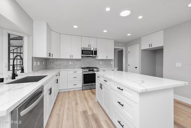 kitchen with a kitchen island, white cabinetry, appliances with stainless steel finishes, and sink