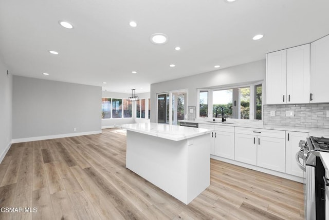 kitchen with sink, a center island, appliances with stainless steel finishes, light stone countertops, and white cabinets