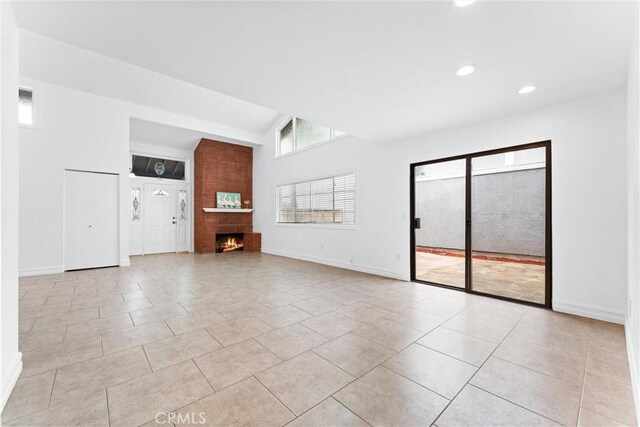 unfurnished living room featuring vaulted ceiling, light tile patterned flooring, and a fireplace