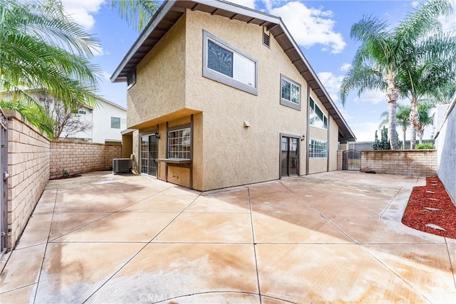 back of property featuring a patio area, a fenced backyard, central AC unit, and stucco siding