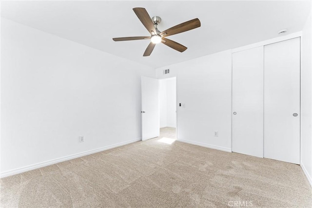 unfurnished bedroom featuring a ceiling fan, a closet, light carpet, and baseboards