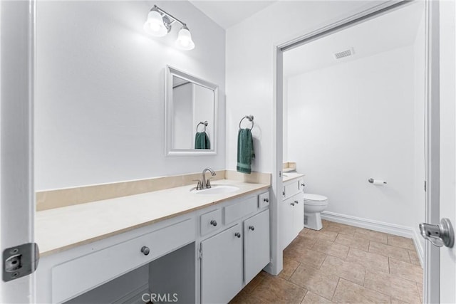 bathroom featuring toilet, baseboards, visible vents, and vanity