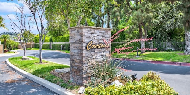 community / neighborhood sign featuring fence and a yard