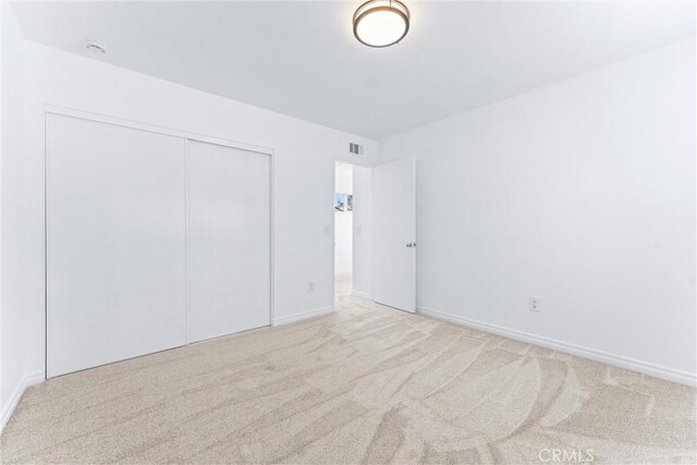 unfurnished bedroom featuring light colored carpet and a closet