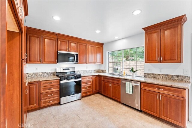 kitchen with light stone counters, stainless steel appliances, and sink