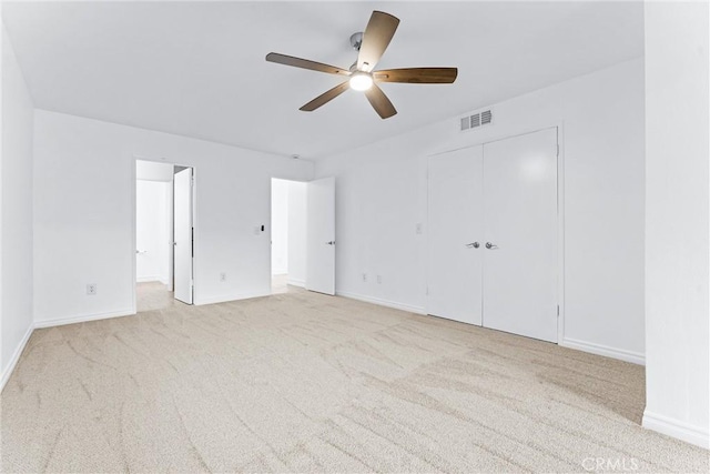 unfurnished bedroom featuring a closet, visible vents, light carpet, and baseboards