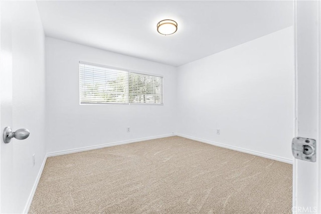 empty room featuring light carpet and baseboards