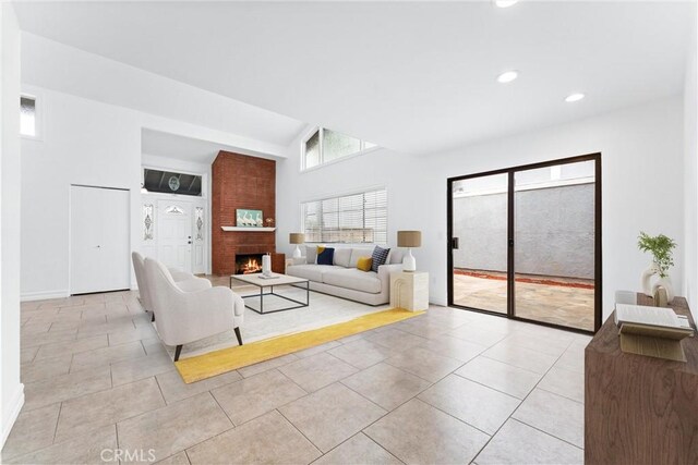 living room with a large fireplace, lofted ceiling, and light tile patterned floors