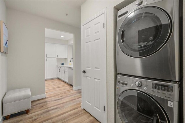 laundry room featuring light hardwood / wood-style floors and stacked washer and clothes dryer