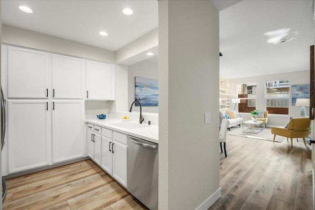 kitchen with white cabinetry, stainless steel dishwasher, sink, and light hardwood / wood-style flooring