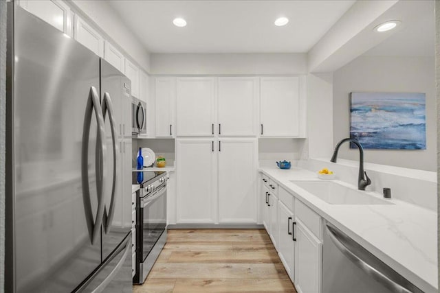 kitchen featuring white cabinetry, sink, light stone counters, and stainless steel appliances