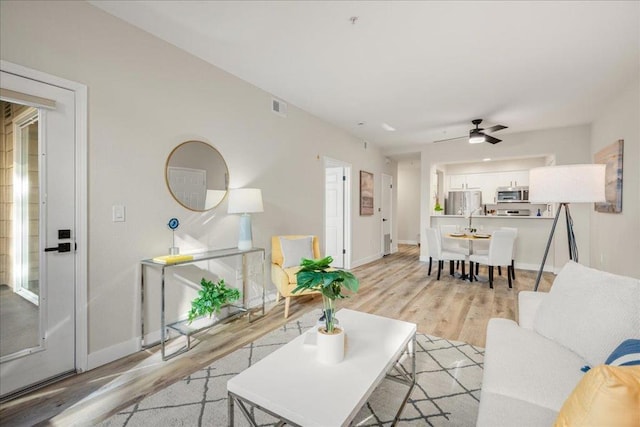 living room featuring ceiling fan and light hardwood / wood-style floors