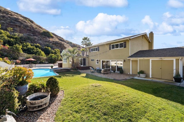 rear view of house featuring a mountain view, a fire pit, and a lawn