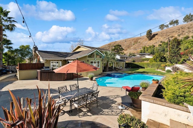 view of pool featuring a mountain view, a patio area, and an in ground hot tub