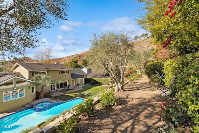 view of swimming pool with a mountain view, a patio area, and an in ground hot tub