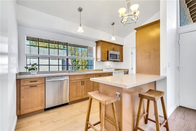 kitchen with sink, hanging light fixtures, stainless steel appliances, a kitchen bar, and kitchen peninsula