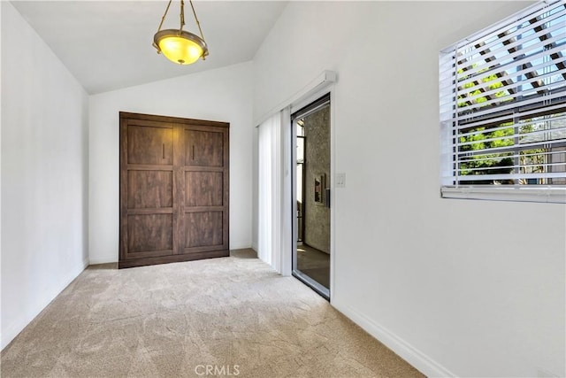 unfurnished bedroom featuring multiple windows, lofted ceiling, access to outside, and light colored carpet