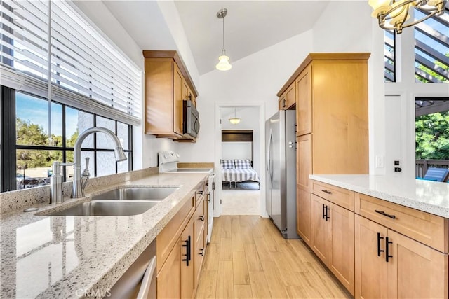 kitchen featuring white electric range, sink, light stone counters, decorative light fixtures, and stainless steel fridge