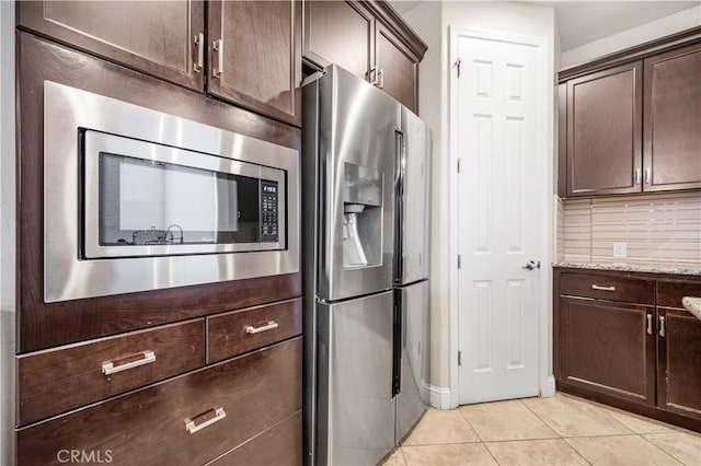 kitchen featuring appliances with stainless steel finishes, light tile patterned floors, light stone counters, and dark brown cabinetry