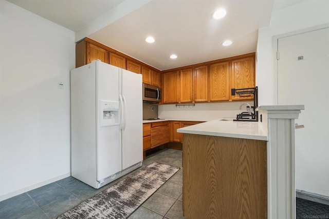 kitchen with cooktop, white refrigerator with ice dispenser, sink, and kitchen peninsula