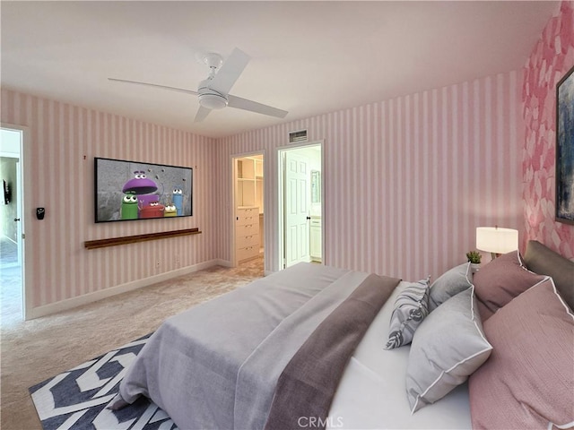 carpeted bedroom featuring ensuite bathroom, a walk in closet, and ceiling fan