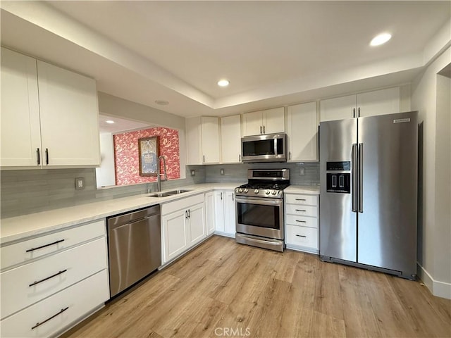 kitchen with white cabinetry, appliances with stainless steel finishes, sink, and backsplash