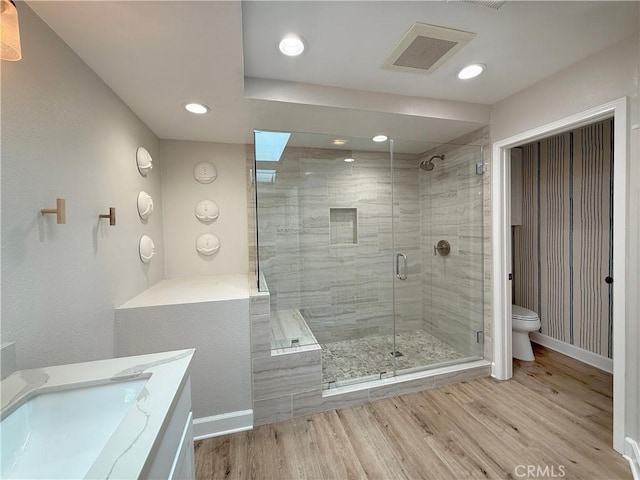 full bath featuring toilet, wood finished floors, visible vents, baseboards, and a stall shower