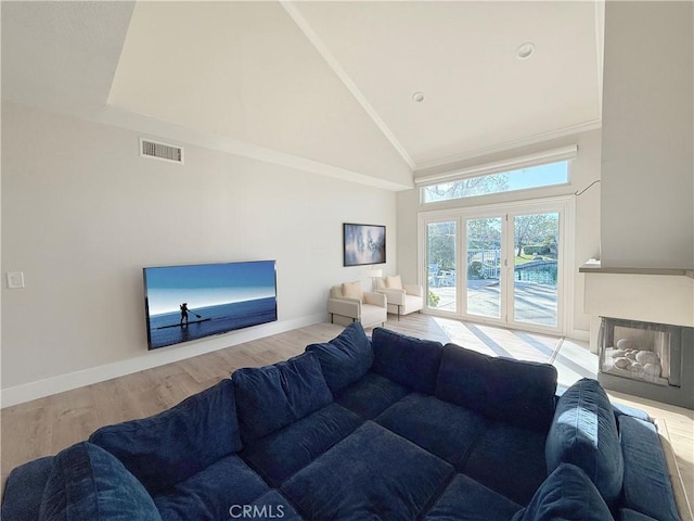 living area with high vaulted ceiling, wood finished floors, visible vents, and baseboards