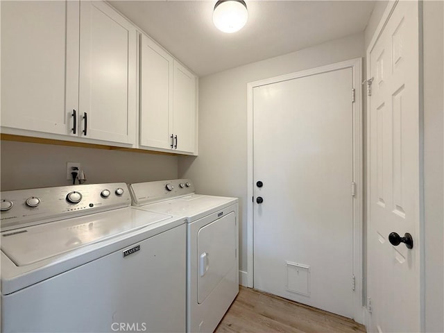 laundry area with washer and dryer, cabinets, and light wood-type flooring