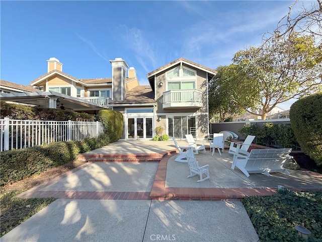 back of property featuring a patio, a balcony, fence, french doors, and stucco siding