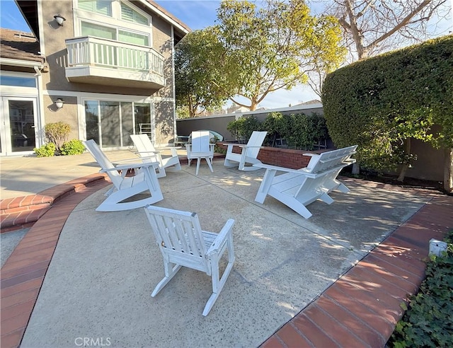 view of patio featuring fence and a balcony