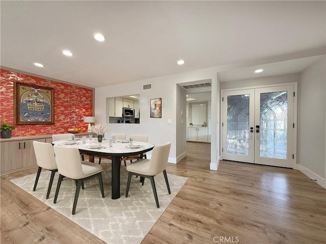 dining area with french doors and light hardwood / wood-style flooring