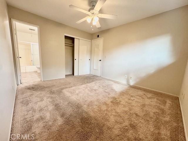 unfurnished bedroom featuring ensuite bath, carpet floors, ceiling fan, and a closet