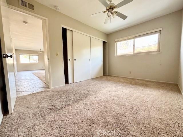 unfurnished bedroom featuring ceiling fan, light carpet, and a closet