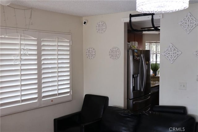 interior space with fridge with ice dispenser and a textured ceiling