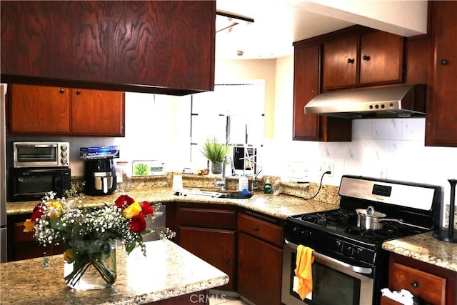 kitchen featuring stainless steel range with gas cooktop, sink, and light stone counters