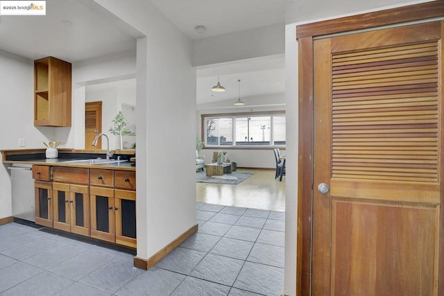 kitchen featuring light tile patterned flooring, sink, stainless steel dishwasher, and decorative light fixtures