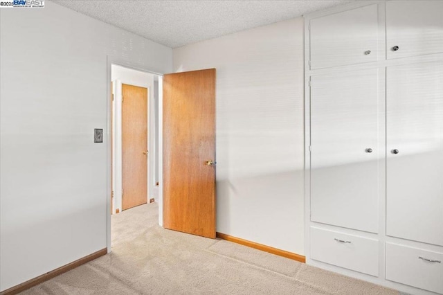 unfurnished bedroom with light colored carpet, a textured ceiling, and a closet