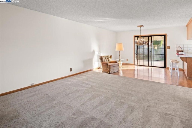 unfurnished room with light carpet, a textured ceiling, and a chandelier