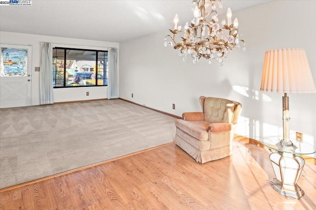 unfurnished room with a notable chandelier, a textured ceiling, and light hardwood / wood-style floors