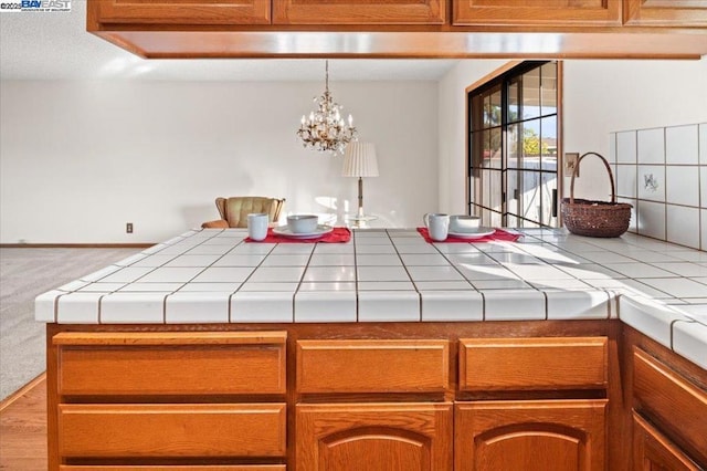 interior space with carpet, tile countertops, and a chandelier