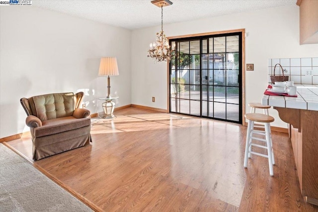 living area with a notable chandelier, light hardwood / wood-style floors, and a textured ceiling