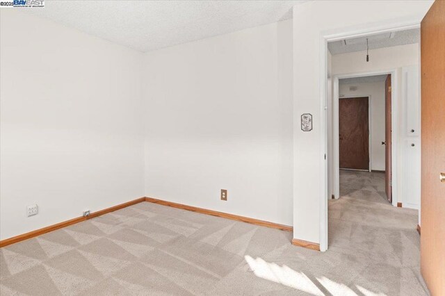 spare room featuring light carpet and a textured ceiling