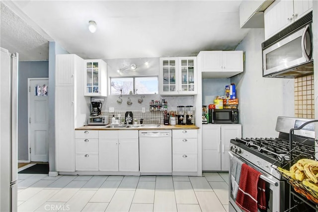 kitchen featuring appliances with stainless steel finishes, sink, white cabinets, and decorative backsplash