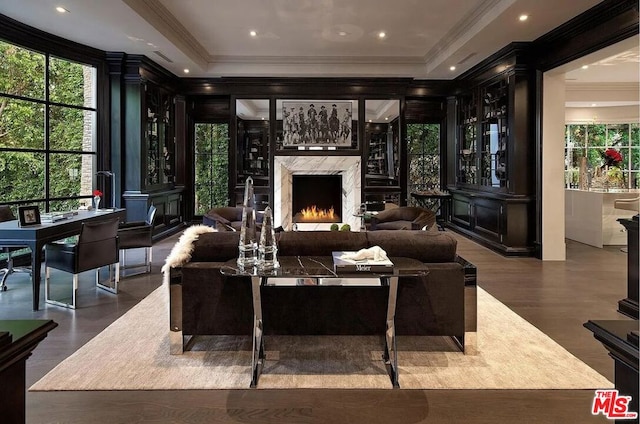 living room featuring crown molding, a tray ceiling, a fireplace, and hardwood / wood-style floors