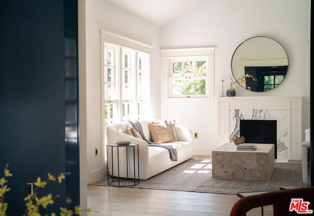 living room featuring hardwood / wood-style flooring, a wealth of natural light, a high end fireplace, and vaulted ceiling