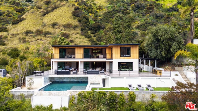 back of house with an outdoor living space, a balcony, and a patio area