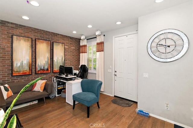 office area with hardwood / wood-style flooring and brick wall