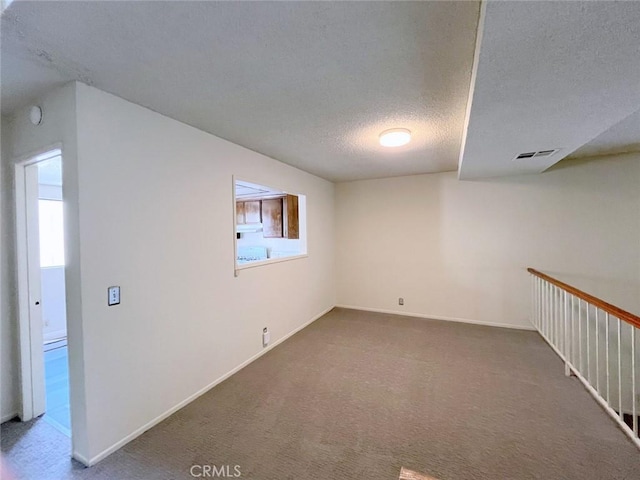 unfurnished room with dark carpet and a textured ceiling