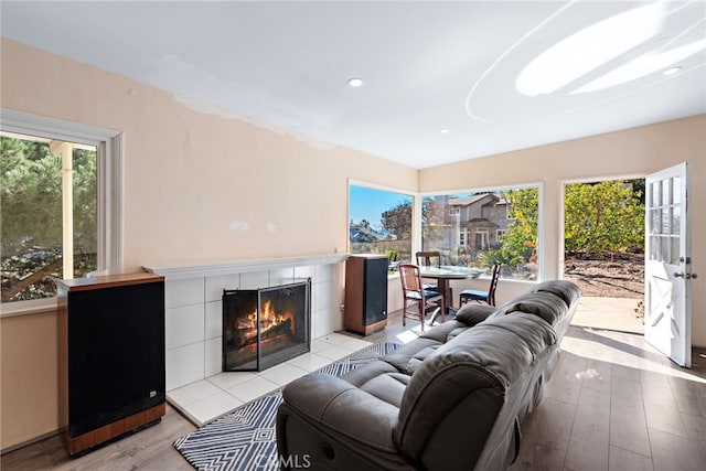 living room featuring a tile fireplace and light wood-type flooring